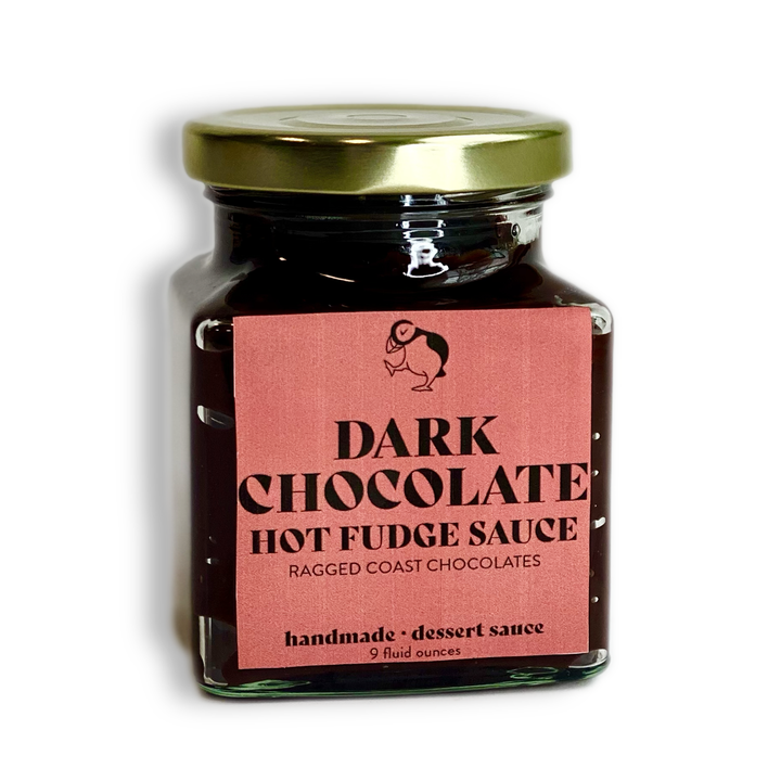 A 9-fluid-ounce glass jar with a golden lid, containing Dark Chocolate Hot Fudge Sauce from Ragged Coast Chocolates. The label indicates it is handmade in micro batches.