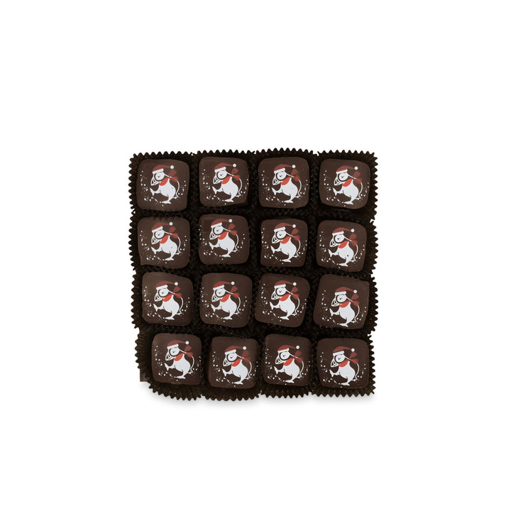 A grid of sixteen Eggnog and Bittersweet Chocolate Truffles for the Holidays from Ragged Coast Chocolates, each adorned with an illustration of a snowman in a red hat and scarf, hides a creamy ganache surprise beneath.