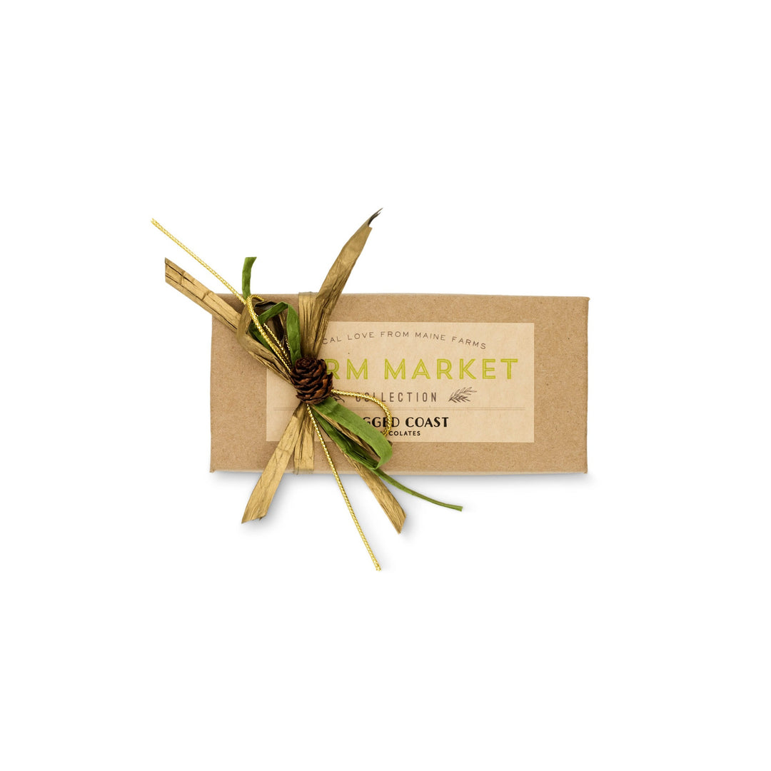 A brown rectangular package labeled "Maine Farm Market Truffle Collection" from Ragged Coast Chocolates is adorned with decorative straw and a small pine cone, offering a hint at the delight inside—luxurious milk chocolate truffles that encapsulate the essence of Maine farm products.