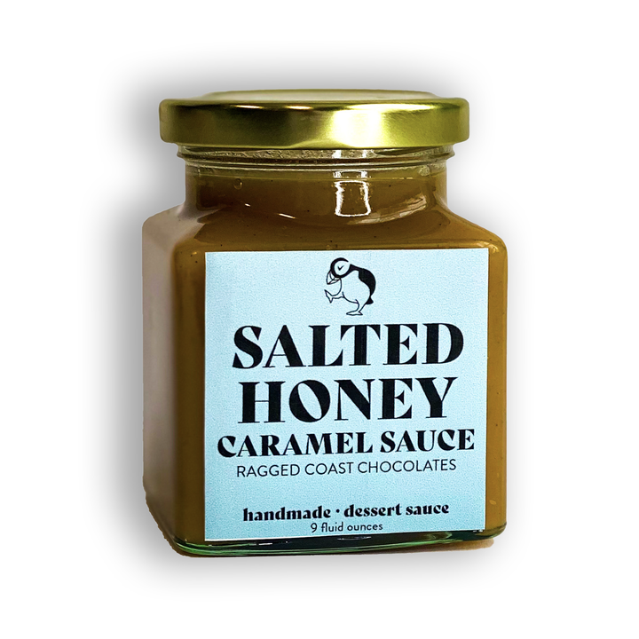 A 9 fluid ounce jar of handmade Salted Honey Caramel Sauce by Ragged Coast Chocolates, featuring a gold lid and a pale blue label.