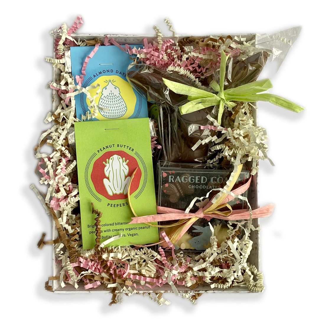 Assorted gourmet direct-trade chocolates and candies in a Ragged Coast Chocolates Easter Gift Box with decorative filler paper.