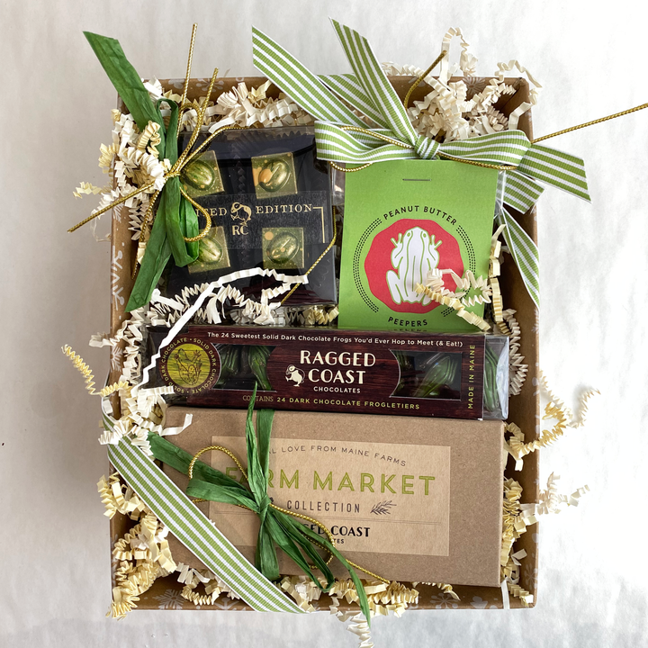 Celebrate Saint Patrick's Day with Ragged Coast Chocolates' Saint Patrick's Day Gift Box. It features wrapped delights, a Farm Market card, and a festive Reese's Peanut Butter Tree, all adorned with green ribbons and paper shreds.