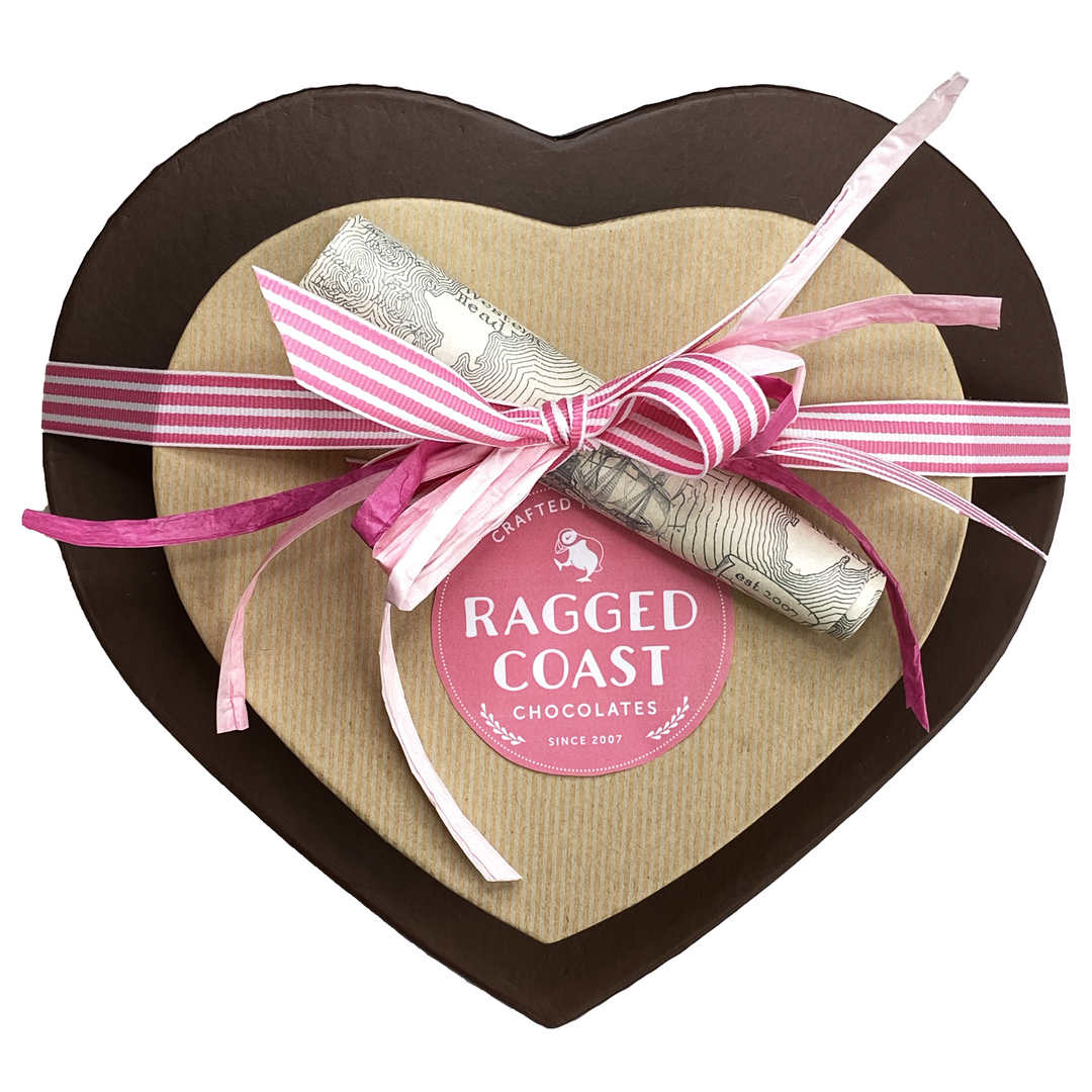 The "Two Hearts - 50 Pieces" by Ragged Coast Chocolates is a heart-shaped box wrapped in pink ribbon and decorative map, concealing an indulgent surprise of rich chocolate truffles.